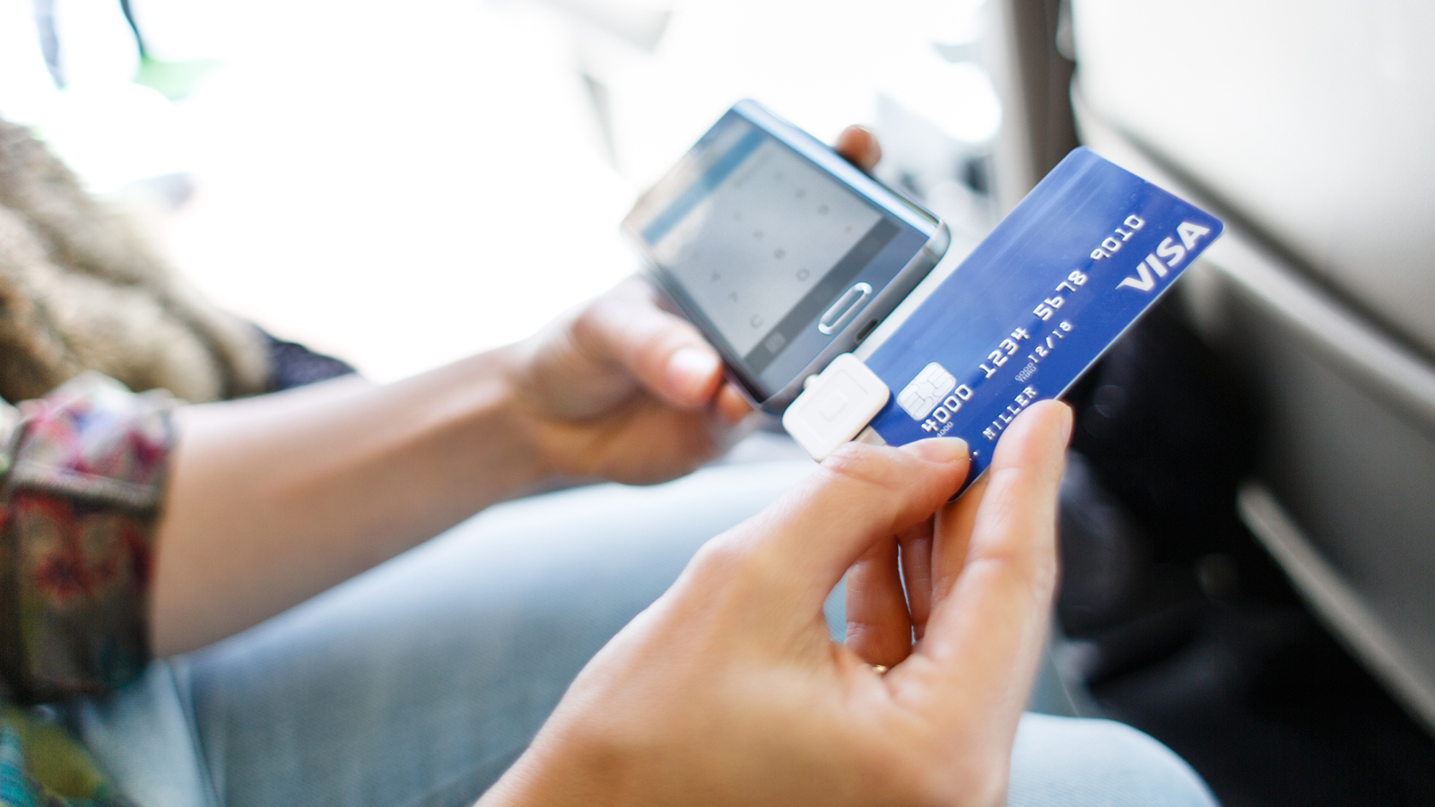A woman swiping a card in a mobile card reader.