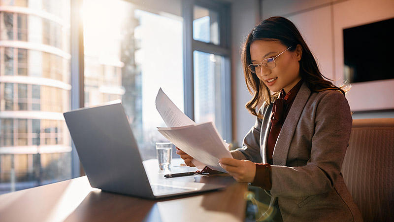 Asian businesswoman analyzing reports while working in office.